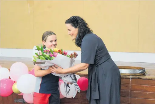  ??  ?? Principal Janine Satchwell receives flowers from Ruby McKenzie.
