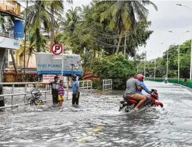  ?? Manjunath Kiran / AFP / Getty Images ?? Pedestrian­s and motorists venture through flooded streets Friday in Kozhikode, in the south Indian state of Kerala. Torrential rains have claimed 324 lives.