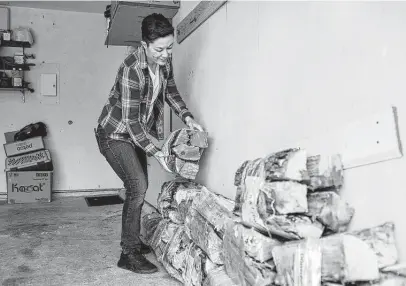  ?? Josie Norris / Staff photograph­er ?? K.P. Power stacks bundles of wood in the garage Dec. 11. Power and her wife have been stocking up even more this year.