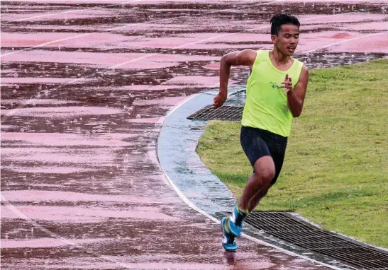  ?? Photo by Jean Nicole Cortes ?? THREAT OF OMPONG. An athlete continues his practice run at the athletic bowl despite the rain. The Batang Pinoy National Finals starts September 17, two days late its schedule due to typhoon Ompong.