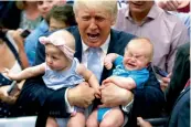  ??  ?? US Republican presidenti­al candidate Donald Trump holds Kellen Campbell of Denver ( right) and Evelyn Keane of Castle Rock during a campaign rally in Colorado on Friday. Mr Trump said he was taking the gloves off and would no more be “Mr Nice Guy”. —