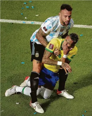  ?? Andres Larrovere - 16.nov.21/afp ?? Nicolas Otamendi tenta levantar o atacante Raphinha após acertar uma cotovelada na boca do brasileiro no empate entre Argentina e Brasil