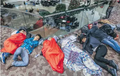  ??  ?? Exhausted travellers sleep in the atrium at Atlanta’s Hartsfield-Jackson Internatio­nal Airport on Monday.