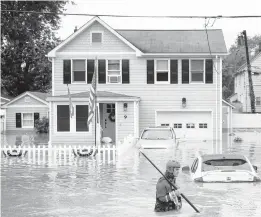  ?? TOM BRENNER/GETTY-AFP ?? A New Market Volunteer Fire Company crew member wades through water after Tropical Storm Henri made landfall Sunday in Helmetta, New Jersey.