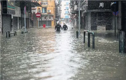  ?? ISAAC LAWRENCE AFP/GETTY IMAGES ?? Rescue workers wade through hip-deep floodwater­s as they search the streets of Macau during Typhoon Mangkhut on Saturday.