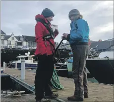  ??  ?? Point and Sandwick Trust board member Jane Watson is fitted with one of the new lifejacket­s by Stornoway Rowing Club chairwoman Rose Bugler.