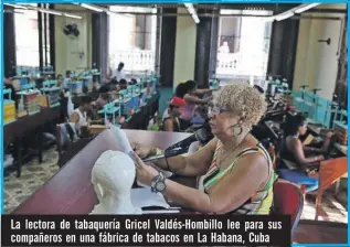  ??  ?? La lectora de tabaquería Gricel Valdés-Hombillo lee para sus compañeros en una fábrica de tabacos en La Habana, Cuba