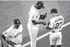  ?? Brett Coomer / Staff photograph­er ?? Astros designated hitter Yordan Alvarez, center, and second baseman Jose Altuve, right, look at their new American League championsh­ip rings on Monday at Minute Maid Park.