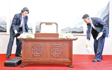  ??  ?? North Korean security guards spray disinfecta­nt and check a desk where a guestbook, to be used by Jong Un, lies before the start of theinter-Korean summit at the Peace House building on the southern side of the truce village of Panmunjom. — AFP photo