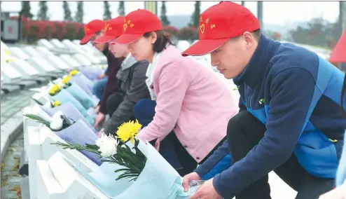  ?? SONG WEIXING / FOR CHINA DAILY ?? Volunteers in Dingyuan county, Anhui province, lay flowers on the graves of revolution­ary martyrs on March 30.