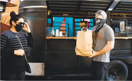  ?? KRISTIAN CARREON ?? Sideyard BBQ co-owner Dennis O’Connor hands a takeout order to Yeimi Rodriguez on Thursday.