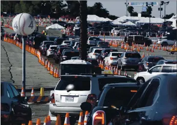  ?? RICHARD VOGEL — THE ASSOCIATED PRESS ?? Cars wait in line as they enter a COVID-19 vaccinatio­n site at Dodger Stadium in Los Angeles on Thursday.