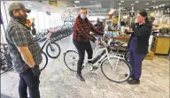  ?? Tony Dejak / Associated Press ?? Store manager Josh Hayden, left to right, talks with Kay Amey and Jackie Gee about a new bicycle at Eddy’s Bike Shop in Willoughby Hills, Ohio.