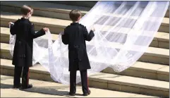  ?? Associated Press photo ?? Pageboys John and Brian Mulroney hold the train of the dress of Meghan Markle as she arrives at the wedding ceremony at St. George’s Chapel in Windsor Castle in Windsor, near London, England, Saturday.