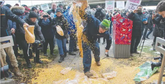  ?? RYAN REMIORZ/THE CANADIAN PRESS ?? Farmers dump corn as they protest the ongoing rail strike in front of the riding office of Prime Minister Justin Trudeau on Monday in Montreal.