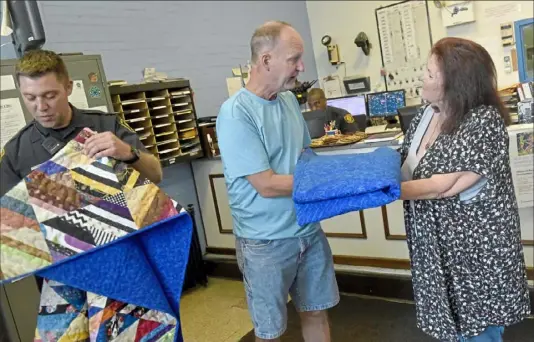  ?? Lake Fong/ Pittsburgh Post- Gazette ?? Pittsburgh police Officers Mike Smidga, left, and Dan Mead receive quilts Monday from Sue Minkus of Three River Quilters at the city’s Zone 4 police station in Squirrel Hill. Both officers were among the first responders injured during the 2018 shooting at Tree of Life synagogue.