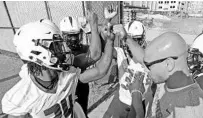  ?? RED HUBER/ORLANDO SENTINEL ?? UCF running backs coach Anthony Tucker, right, huddles with players before a practice. Tucker was promoted to co-offensive coordinato­r.