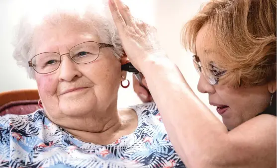  ?? | KHN ?? Janie York examines the ear of Elaine Martin at the SilverRidg­e Assisted Living facility in Gretna, Neb., on Aug. 15. Martin had “quite a bit” of earwax before getting her ears cleaned by York and getting hearing aids, at her daughter’s urging.