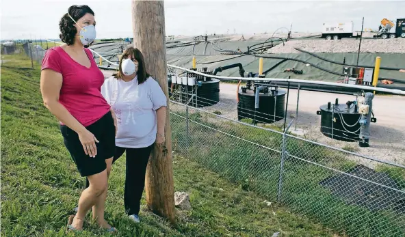  ?? FOTO: GETTY IMAGES ?? Dawn Chapman (links) und Karen Nickel vor dem Zaun zur Müllkippe West Lake in St. Louis. Aus Angst vor radioaktiv­en Partikeln tragen die beiden Frauen Schutzmask­en.