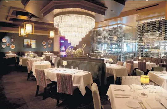  ?? AMY BETH BENNETT/SUN SENTINEL PHOTOS ?? A wall of wine defines the main dining room at Eddie V’s restaurant in the 100 Las Olas tower in downtown Fort Lauderdale.