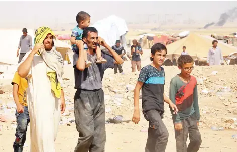  ??  ?? Displaced Syrians from Deir Ezzor walk at a makeshift camp, some 7 km from Arisha in the neighborin­g province of Hasakah on Aug. 13.