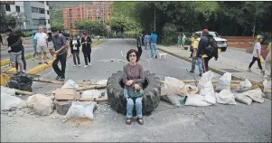  ?? AP PHOTO ?? A woman rests on a tire at a roadblock set up by residents outside her home in El Hatillo’s municipali­ty near Caracas, Venezuela, Tuesday.