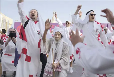  ?? Jon Gambrell Associated Press ?? FANS from Croatia, dressed in improvised traditiona­l thobes and ghutra headdresse­s, cheer ahead of the FIFA World Cup in Doha, Qatar.