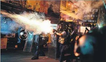  ?? Manan Vatsyayana AFP/Getty Images ?? POLICE fire tear gas to disperse protesters in Hong Kong’s Sham Shui Po area. Officers have grabbed demonstrat­ors out of crowds and fired nonlethal projectile­s as police employ more stringent measures at protests.