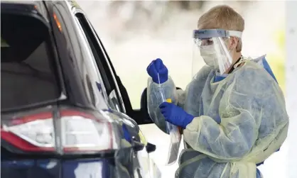  ?? Photograph: Nathan Denette/AP ?? A healthcare worker conducts a Covid-19 test at a drive-thru center in Toronto. Canadian authoritie­s will continue using the nose swab method for younger children or those who can’t follow the swish, gargle and spit instructio­ns.