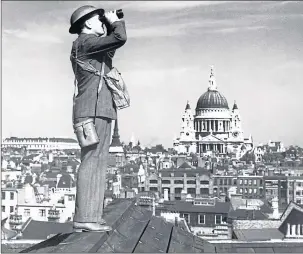  ??  ?? Aircraft spotter stands on roof of a building in London in front of St Paul’s Cathedral in 1940