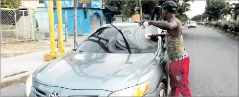  ??  ?? Joven limpia vidrios afirma que se gana diariament­e entre 500 a 700 en la Avenida Caamaño, en La Romana.