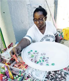  ?? LIONEL ROOKWOOD/PHOTOGRAPH­ER ?? A vendor with a tray of sweets outside the gate of a Corporate Area school.