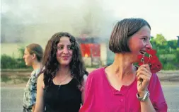  ?? ALEXANDRA BOULAT ?? Two young Kosovar Albanian girls celebrate liberation by NATO troops as Serbs’ homes behind them are burning in this photo from 1999.