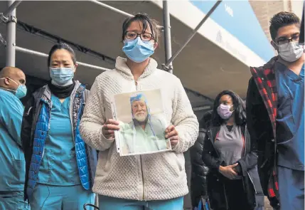  ??  ?? Mount Sinai Hospital workers hold up photos of medical workers who have died from the coronaviru­s during a protest Friday in New York. Medical workers were protesting the lack of personal protective equipment during a surge in coronaviru­s cases.