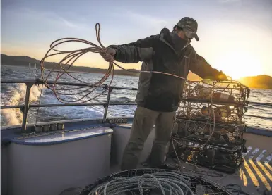  ?? Photos by Stephen Lam / The Chronicle ?? Michael Cabanas coils a rope as he prepares crab pots aboard the Huli Cat in Half Moon Bay.