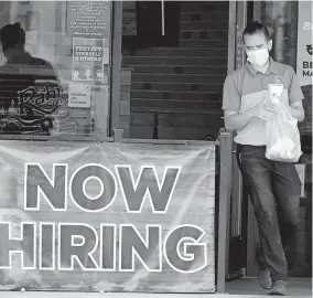  ?? ASSOCIATED PRESS FILE PHOTO] [LM OTERO/ ?? A customer wears a face mask as they carry their order past a now hiring sign Sept. 2 at an eatery in Richardson, Texas. The number of Americans seeking unemployme­nt benefits fell last week to 751,000, the lowest since March, but it's still historical­ly high and indicates the viral pandemic is still forcing many employers to cut jobs.