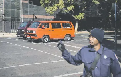  ?? Picture: Jacques Nelles ?? KEEPING THE PEACE. A Metro police officer is seen near a damaged taxi on Madiba Street where a shoot-out between taxi drivers took place. Five taxi drivers were injured during the attack in Pretoria.