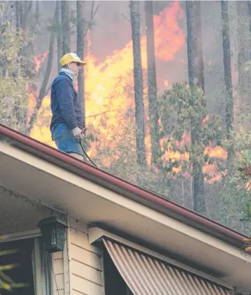  ??  ?? BURNING ISSUE: A homeowner fights to save his house from a fire near the Gold Coast.