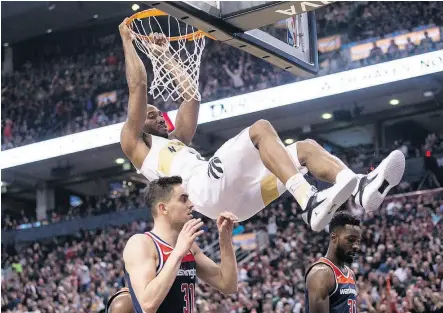  ?? CHRIS YOUNG / THE CANADIAN PRESS ?? Toronto Raptors forward Kawhi Leonard hangs from the basket after scoring on Friday night.