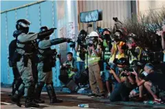  ??  ?? Des policiers anti-émeute sous l’oeil de journalist­es à Hongkong, le 27 octobre.(KIM KYUNG-HOON/REUTERS)