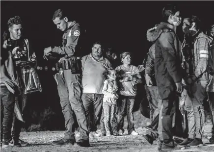  ?? Brandon Bell / Getty Images ?? A migrant family waits to be processed Thursday in Roma. Gov. Greg Abbott says the increased flow of immigrants into the country warrants a change of law that would allow barring the funding for the education of children living here illegally.