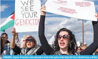  ?? – AFP ?? LIMASSOL, Cyprus: Protesters raise placards in front of the gates of the Royal Air Force Akrotiri base, a British overseas territory, as they rally against its alleged use to supply the Zionist war in Gaza on Jan 14, 2024.