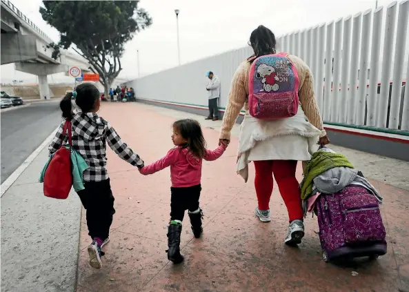  ??  ?? A Mexican migrant mother and her daughters walk to the port of entry into the United States in Tijuana for an asylum hearing yesterday. The Trump administra­tion’s controvers­ial zero-tolerance policy saw an increase in the number of migrant children...