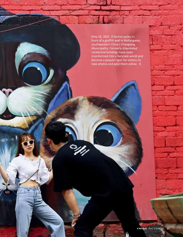  ?? ?? May 18, 2021: A tourist poses in front of a graffiti wall in Mafangwan, southweste­rn China’s Chongqing Municipali­ty. Formerly dilapidate­d residentia­l buildings have been transforme­d into a fairytale world and become a popular spot for visitors to take photos and post them online. IC