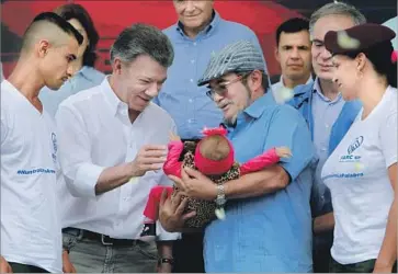  ?? Mauricio Duenas Castaneda European Pressphoto Agency ?? COLOMBIAN President Juan Manuel Santos greets a baby held by FARC commander Rodrigo Londono at a ceremony celebratin­g the end of the nation’s half a century of conf lict. “Peace is irreversib­le,” Santos said.