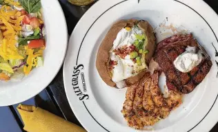  ?? ?? The Gulf Coast Steak & Shrimp plate at Saltgrass Steak House — a sirloin steak, garlicky grilled shrimp, a loaded baked potato and a salad — won’t break the bank.