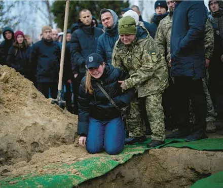  ?? DANIEL COLE/AP ?? Anna Korostensk­a falls to her knees Jan. 19 in Bucha before the grave of her fiancee, Oleksii Zavadskyi, who died in combat four days earlier.