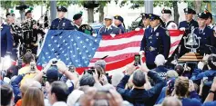  ?? — Reuters photo ?? Police and Fire Department officers hold an American flag that flew over the World Trade Centre at the National 911 Memorial and Museum during ceremonies marking the 16th anniversar­y of the Sept 11, 2001 attacks in New York.
