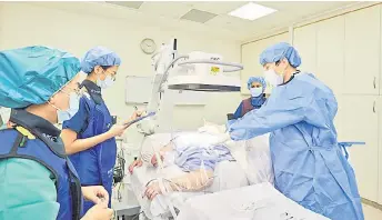  ?? ?? Dr Lim performs a staged procedure to dull pain in the spine. The nurses and radiograph­er wear protective vests as a fluoroscop­e, essentiall­y an x-ray, is used to help pinpoint the exact area of pain.