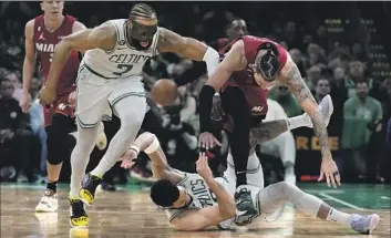  ?? Charles Krupa Associated Press ?? JAYLEN BROWN (7) and Jayson Tatum of the Celtics battle Miami’s Caleb Martin for a loose ball in the first half of Game 1 of the Eastern Conference finals. Tatum scored 30 but didn’t take a shot in the fourth quarter.